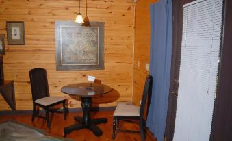 a cozy wooden cabin with blue curtains , wooden walls , and a dining table surrounded by chairs at River Valley Rentals