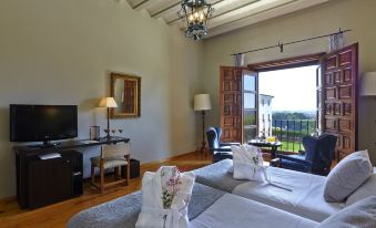 a room with two beds , a couch , and a tv . the room is well - lit and has a view of the outdoors at Parador de Zamora