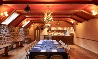 a long dining table with blue tablecloths and chairs is set up in a room with wooden walls at Loch Kinord Hotel
