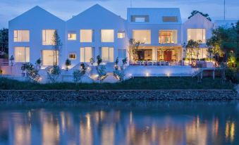 a large white house with a pool in the backyard , surrounded by trees and grass at Sala Ayutthaya