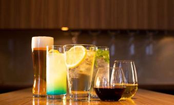 a wooden table with four glasses filled with various drinks , including beer and lemonade , placed next to each other at Oarks Canal Park Hotel Toyama