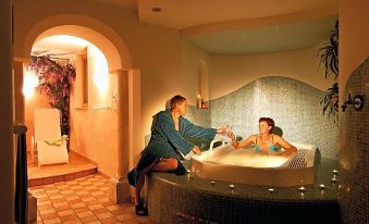 a man and a woman are relaxing in a large bathtub filled with water , enjoying each other 's company at Hotel Goldener Adler