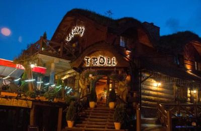 "a nighttime scene of a restaurant called "" troll "" with a staircase leading up to it" at Troll