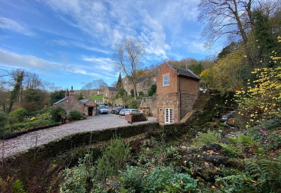 a brick house situated on a hillside , surrounded by trees and bushes , with a car parked in front of it at Robin Hood Farm B&B