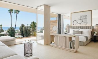 a luxurious bedroom with large windows offering a view of the ocean , white furniture , and an open balcony at Ikos Andalusia