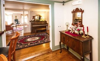 a cozy living room with hardwood floors , a piano in the corner , and a mirror hanging on the wall at Rosewood Country Inn
