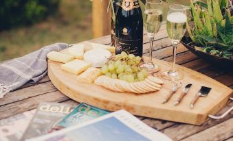 a wooden dining table with a wine bottle , cheese platter , and magazines placed on it at Nature Domes