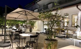 an outdoor dining area with tables and chairs , surrounded by potted plants and a staircase at Seebay Hotel