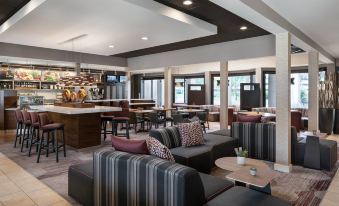 a modern lounge area with a couch , chairs , and tables in front of a bar at Courtyard Pleasanton