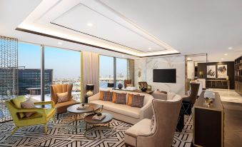 a modern living room with a large window overlooking the city , featuring a couch , chairs , and a dining table at Waldorf Astoria Kuwait