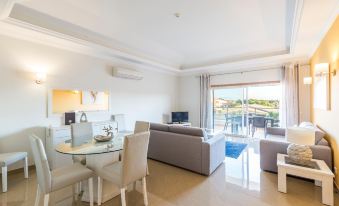 a modern living room with a glass table and chairs , a couch , and sliding glass doors leading to an outdoor terrace at Lakeside Country Club - Apartamentos Turísticos