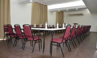 a conference room with several chairs arranged in a semicircle around a table , and a television mounted on the wall at Hotel Nacional Inn Aracatuba