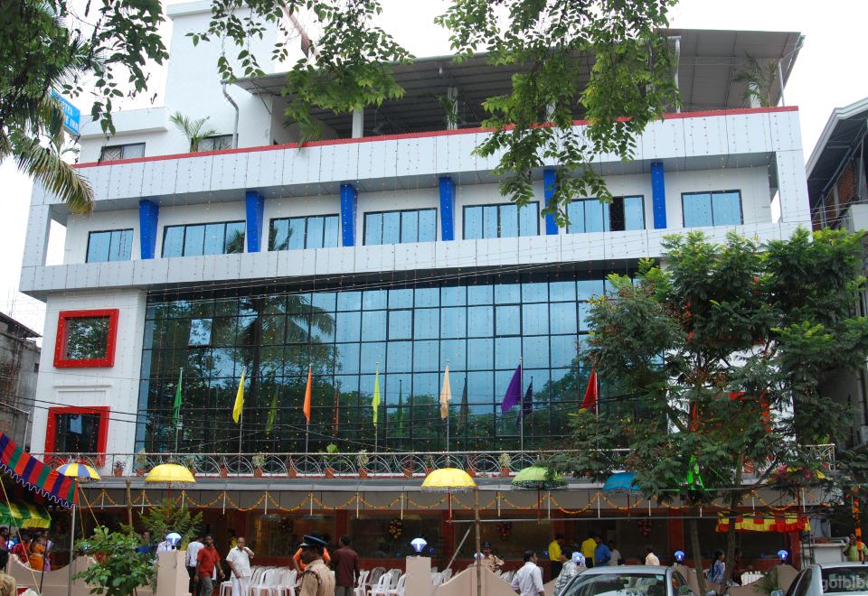 a large building with many flags and people walking in front of it , under a tree at Hotel Palace Inn