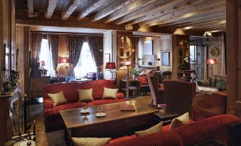 a cozy living room with wooden furniture , including a couch and chairs , and a dining table at Hotel Mont Blanc