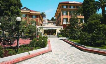 a hotel with multiple buildings , trees , and a paved walkway leading up to the entrance at Hotel Le Palme