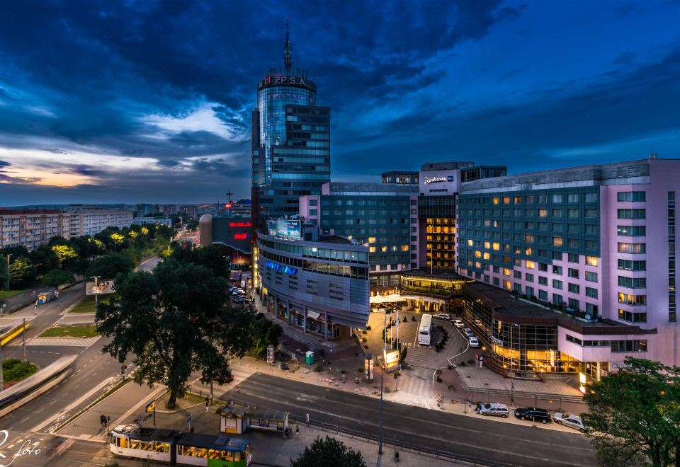 a city street at night with tall buildings , traffic , and cars , illuminated by blue lights at Radisson Blu Hotel, Szczecin