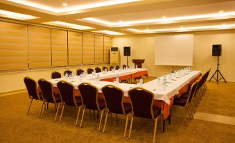 a conference room set up for a meeting , with several chairs arranged in a semicircle around a long table at Gardenia Hotel