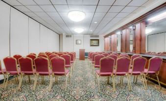 a conference room with red chairs arranged in rows and a podium at the front at Ramada by Wyndham Metairie New Orleans Airport
