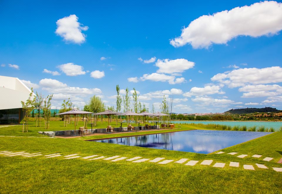 a large grassy field with a pond in the middle , surrounded by a wooden fence at L'And Vineyards