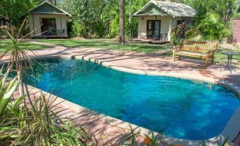 a backyard with a pool and a house , surrounded by trees and grass , under a clear blue sky at Breeze Holiday Parks - Mary River