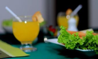 a dining table with a plate of lettuce , a cup of orange juice , and a glass of lemonade at Seasons Villa