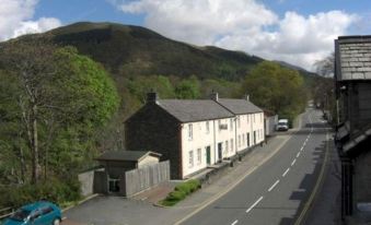 a small town with a road running through it , surrounded by houses and mountains in the background at The Babbling Brook