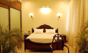 a large bed with a wooden headboard and white linens is situated in a room with two lamps on either side at The Avalon, Durg