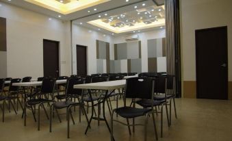 a large , empty conference room with rows of chairs and tables , under the illumination of modern lights at Yhotel