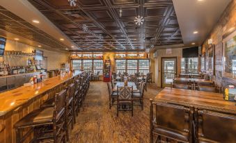 a large wooden restaurant with multiple dining tables and chairs , as well as a bar area at Grand Ely Lodge