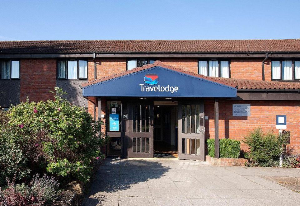 "a building with a blue sign that says "" travelodge "" and a brick exterior under a clear blue sky" at Travelodge Ludlow Woofferton