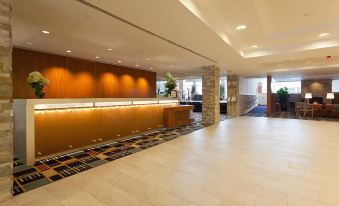 a modern hotel lobby with a reception desk , marble floors , and large windows leading to the outside at UMass Lowell Inn and Conference Center