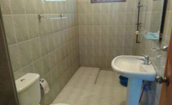 a small bathroom with beige tiles , a white toilet , and a shower area with a window at Rivers Edge