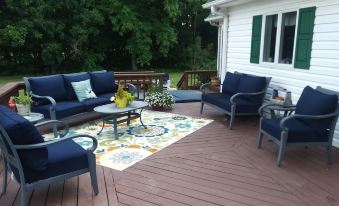 a wooden deck with a variety of blue and white patio furniture , including couches , chairs , and a dining table at Marvels on the Creek