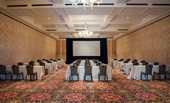 a large conference room set up for a meeting , with multiple tables and chairs arranged in rows at Royal Park Hotel