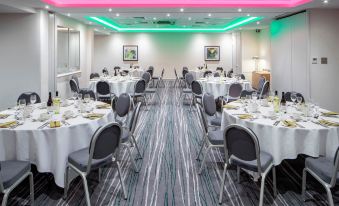 a large banquet hall with multiple tables set for a formal event , including white tablecloths and chairs at Holiday Inn Aylesbury