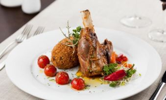 a white plate with a rack of lamb , potatoes , and cherry tomatoes , accompanied by a fork and knife at Nayara Alto Atacama
