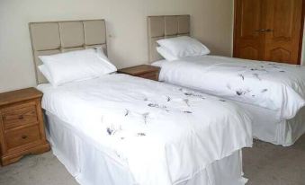 a bedroom with two twin beds , each made up with white sheets and pillows , and the room has wooden doors at Tayberry