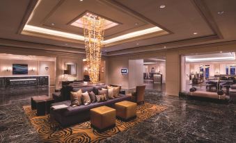 a luxurious hotel lobby with a large chandelier hanging from the ceiling , multiple couches and chairs , and a marble floor at The Ritz-Carlton, Marina del Rey