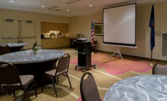 a conference room with a projector screen , tables , and chairs , as well as a bar area at Hilton Garden Inn Kennett Square