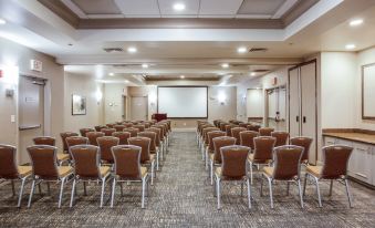 a large conference room with rows of chairs arranged in a semicircle , and a projector screen mounted on the wall at Hilton Garden Inn Nashville/Smyrna