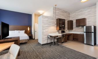 a modern hotel room with a bed , kitchenette , and dining area , all decorated in neutral colors at Residence Inn Riverside Moreno Valley
