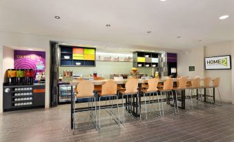 a modern restaurant with wooden tables and chairs , a bar area , and a colorful display at Home2 Suites by Hilton Pittsburgh/McCandless