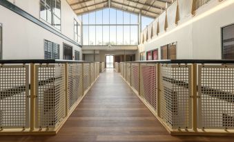 a long hallway with wooden floors and a large window at the end , leading to an open space at Oaks Sydney Goldsbrough Suites