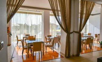 a room with large windows and a wooden floor , featuring a table with chairs in the foreground at E-Hotel Larnaca Resort & Spa