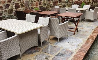 an outdoor dining area with several tables and chairs arranged in a courtyard setting , surrounded by a stone wall at Halfway House Inn