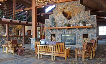 a rustic fireplace with a moose mounted on the wall and a log cabin - like building in the background at The Waters of Minocqua