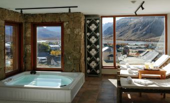 a modern bathroom with a large bathtub and a view of mountains outside the window at Los Cerros del Chalten Boutique Hotel