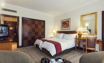 There is a large bed in the middle room of the hotel, accompanied by a table and chairs at Carnival City Hotel