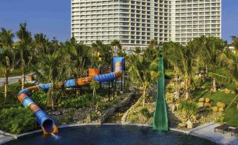 a water park with a large pool , slides , and palm trees in front of a hotel at Movenpick Resort Cam Ranh