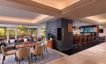 a modern lounge area with a stone wall , wooden furniture , and large windows offering views of the outdoors at Lisbon Marriott Hotel